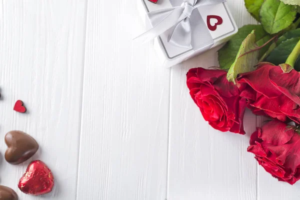Valentines koncept s kyticí růží a zabalený dárek na dřevěný stůl — Stock fotografie