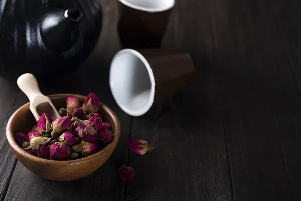 Té de capullos de rosa en tazón de madera con tetera —  Fotos de Stock