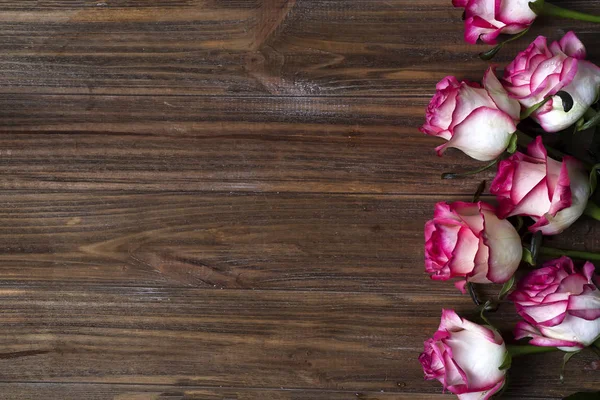 Moldura de rosas em fundo marrom de madeira — Fotografia de Stock