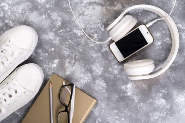 Yaz tatil kavramı: akıllı telefon, beyaz spor ayakkabı, not defteri, kulaklık, kalem