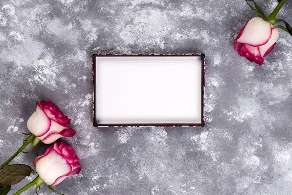 Floral frame: bouquet of pink white roses on stone background with copy space for text.