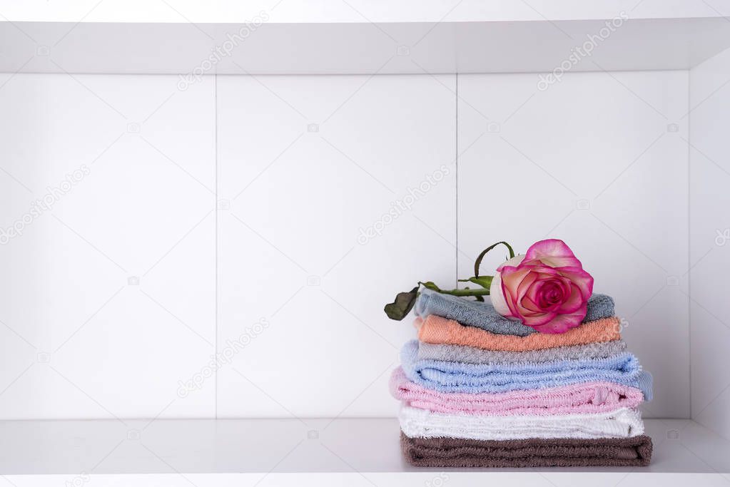 Stack of bath towels with rose on light background