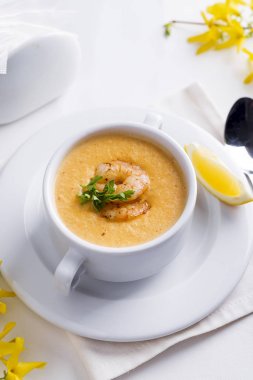 Deniz ürünleri ve beyaz zemin üzerine limon kremalı domates çorbası.
