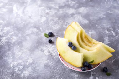 Olgun kavun açık bir taş renkli bir tabağa dilimlenmiş