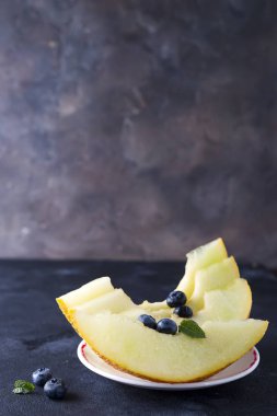 karanlık bir taş zemin üzerine bir plaka üzerinde olgunlaşmış kavun dilimli