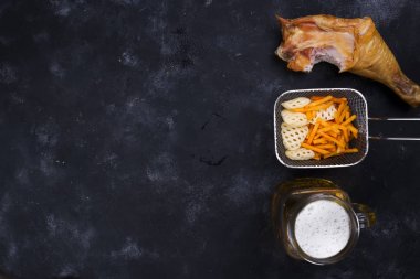 bir bardak bira, aperatifler ve Füme tavuk budu siyah bir zemin üzerine yan