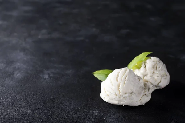 vanilla ice cream ball with green leaves on dark