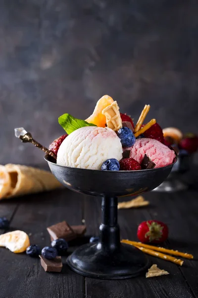 Cuenco con helado con tres cucharadas diferentes de blanco, amarillo, colores rojos y cono de gofre, chocolate, mandarinas y pajitas — Foto de Stock