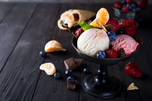 Bowl with ice cream with three different scoops of white, yellow, red colors and waffle cone, chocolate, tangerines — Stock Photo, Image