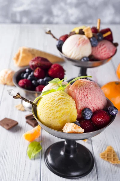 Cuenco con helado con tres cucharadas diferentes de color amarillo, rojo y cono de gofre, chocolate , —  Fotos de Stock