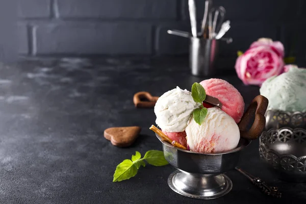 Ванільне і рожеве морозиво в мисці з замороженими ягодами і вафельним конусом — стокове фото