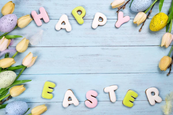 Carta de galletas de Pascua Feliz Pascua y huevos coloridos con tulipanes sobre fondo de madera — Foto de Stock
