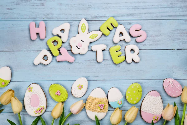 Easter cookies letter Happy Easter and colorful eggs with tulips on wood background — Stock Photo, Image