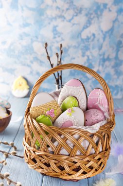 Paskalya kurabiyeleri mavi ahşap arka plan üzerinde ahşap sepet içinde dekore edilmiş