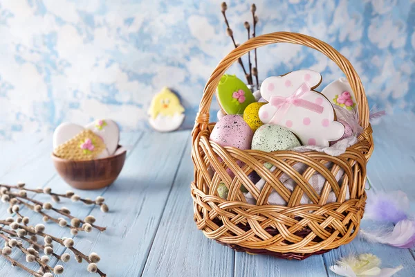Pasen cookies, konijntjes en veelkleurige Pasen eieren in een mand op lichte blauwe achtergrond — Stockfoto