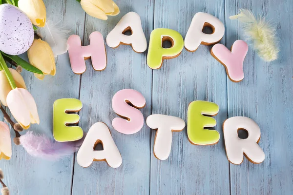 Carta de galletas de Pascua Feliz Pascua y huevos coloridos con tulipanes sobre fondo de madera — Foto de Stock