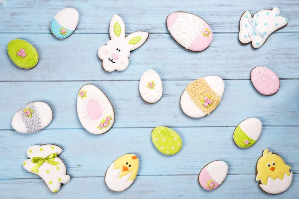 Coloridas galletas de Pascua por todo el fondo azul de madera . — Foto de Stock