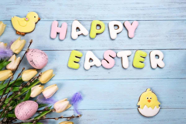 Feliz Pascua letras coloridas Feliz Pascua de galletas de jengibre y galletas de pollo sobre fondo azul de madera . — Foto de Stock