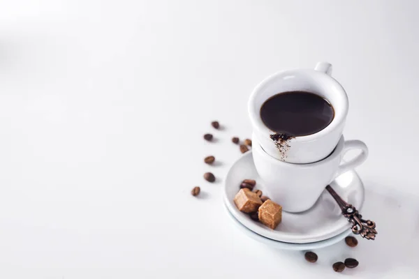 Tasse de café noir sur une soucoupe avec du sucre brun sur fond blanc — Photo