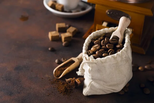 Kaffekvarn, kopp kaffe och kaffe bönor väska i bakgrunden. — Stockfoto