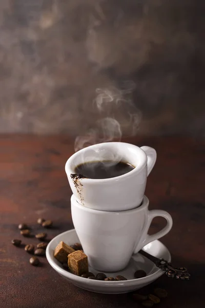 Kopp svart kaffe på ett tefat med brunt socker på sten brun bakgrund — Stockfoto