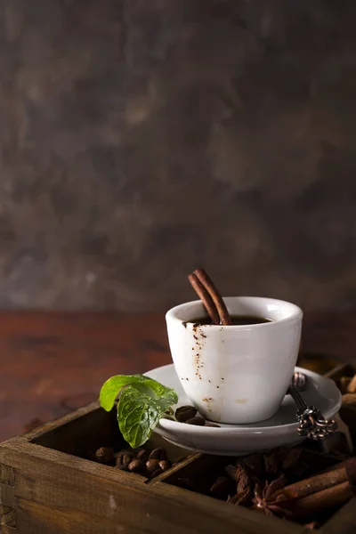 Kopje koffie met cooffee bonen op een houten doos met korrels van koffie en kruiden op een stenen achtergrond — Stockfoto