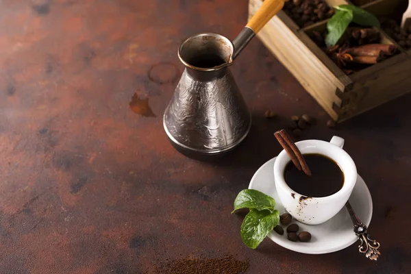 Kopje koffie met cooffee bonen, houten kist met korrels van koffie en kruiden, cezve op een stenen achtergrond — Stockfoto