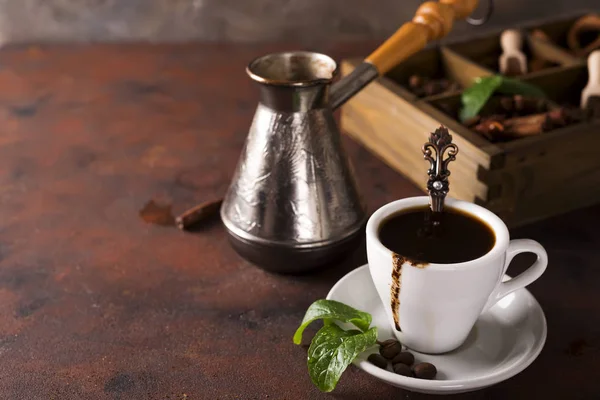 Kopje koffie met cooffee bonen, houten kist met korrels van koffie en kruiden, cezve op een stenen achtergrond — Stockfoto