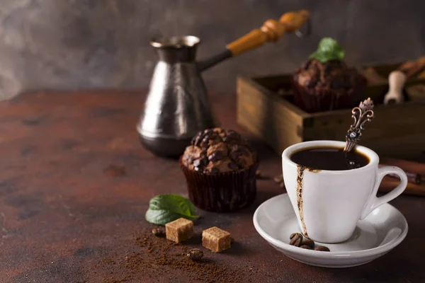 Kopje koffie met cooffee bonen, houten kist met korrels van koffie en kruiden, cupcake op een stenen achtergrond — Stockfoto