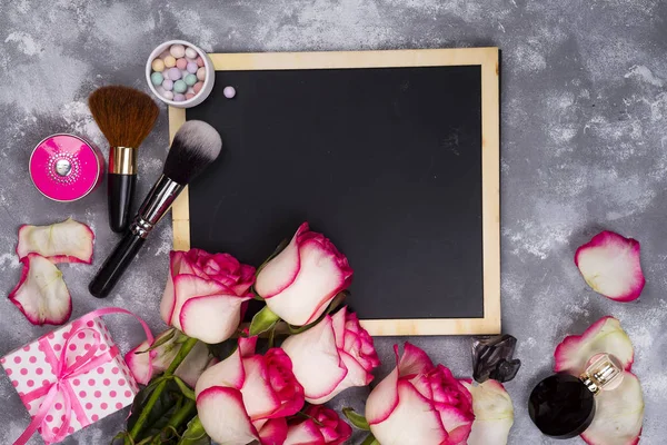 Roses and decorative cosmetics with a chalkboard — Stock Photo, Image