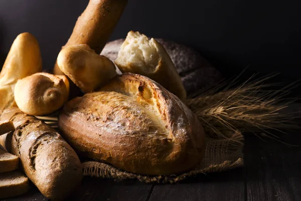Piekarnia - złota wypiek chlebów rustykalne chleb i bułeczki na czarnym tle. — Zdjęcie stockowe