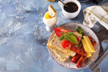 İngiliz kahvaltısı. Kızarmış yumurta, sosis, tost, domates taş masada.
