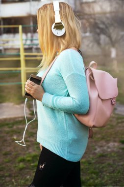 Bir cep telefonu ve şehir içinde müzik dinlemek için kulaklık kız bağlanır