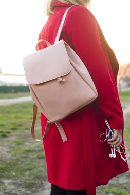 büyük pembe sırt çantası ve telefon kulaklık şık Kırmızı paltolu kızın kolundan ile