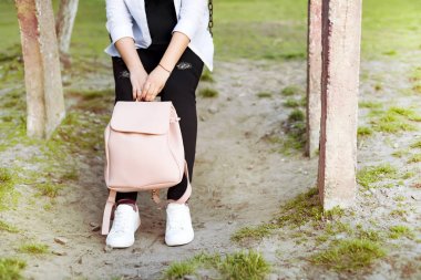 Bayan kot pantolon ve spor ayakkabı, sırt çantası ve akıllı telefon bacaklarda