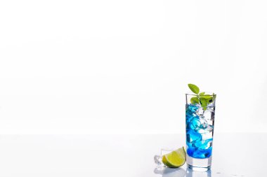 Mavi alkollü içki, üzerinde beyaz izole yakın çekim ile kokteyl cam kaynaklanıyordu. Örnek metin ile tasarım şablonu