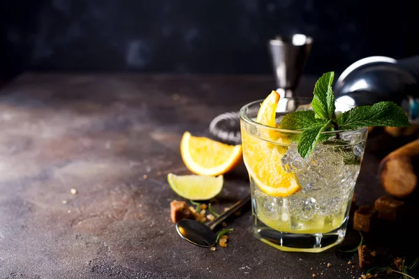 Verfrissend koude alcoholische zomer citrus cocktail met sinaasappel, pepermunt en crushed ijs in stemless glazen — Stockfoto