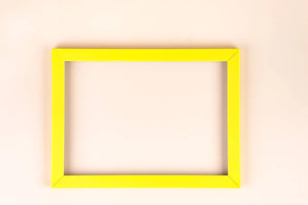Yellow frame isolated on beige background with copy space, flat lay