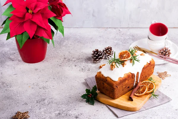 Ovocný bochník poprášený polevou, ořechy a suchým pomerančem na kamenném pozadí. Vánoce a zimní dovolená Poinsettia na pozadí — Stock fotografie