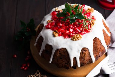 Christmas chocolate cake with white icing and pomegranate kernels on a wooden dark background with red lantern