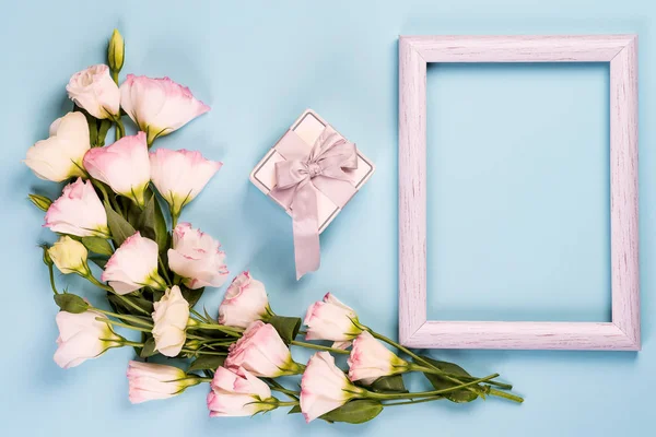 带礼品盒的粉红色花朵的束，以及带复制空间的漂白珊瑚纸背景框架。 平铺，复制空间 — 图库照片