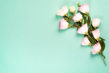 Merkezinde pembe Eustoma 'dan yapılmış boş bir boşluk olan çerçeve kompozisyonu düz yatıyordu. Yeşil arka planda çiçekli dekoratif köşeler.
