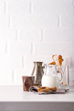 Evde, beyaz mutfak duvarına karşı taş bir tezgahın üzerinde içki yapmak için bir sürahi süt ve kahve.