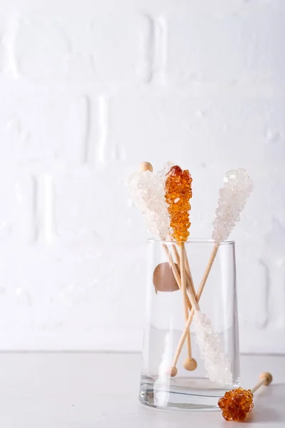 Bonbonbrauner und weißer Zucker auf einem Stick in Glas auf weißem Hintergrund. — Stockfoto