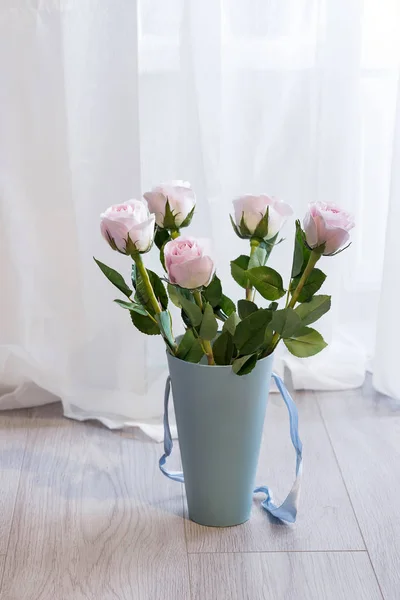 漂亮的粉红色玫瑰束，装在靠近窗户和窗帘的地板上的一个蓝色礼品盒里 — 图库照片