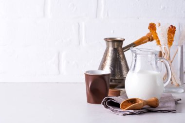 Evde, beyaz mutfak duvarına karşı taş bir tezgahın üzerinde içki yapmak için bir sürahi süt ve kahve.