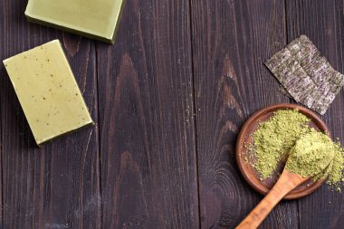 Yeşil zeytinyağı sabunları, yeşil toz ve koyu ahşap arka planda kuru deniz yosunu.,