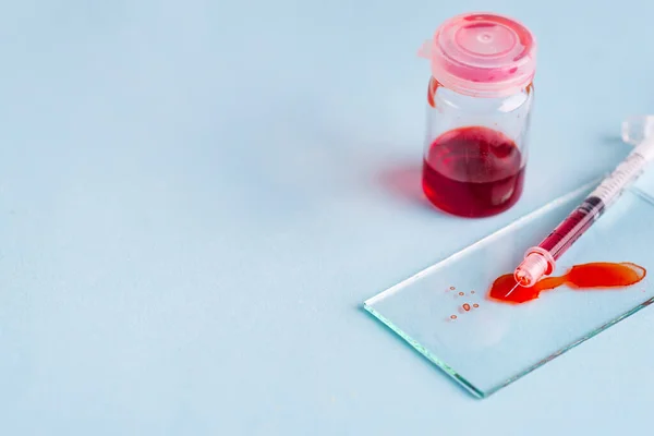 Tubos de ensayo con sangre en laboratorio sobre fondo azul — Foto de Stock