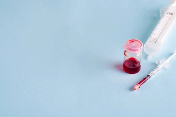 Tubos de ensayo con sangre en laboratorio sobre fondo azul — Foto de Stock