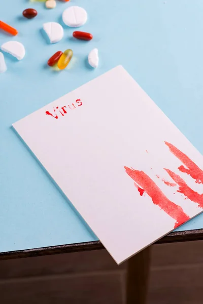 Jeringas, pastillas y tubo de ensayo con sangre sobre un fondo azul con papel blanco y la inscripción Virus — Foto de Stock